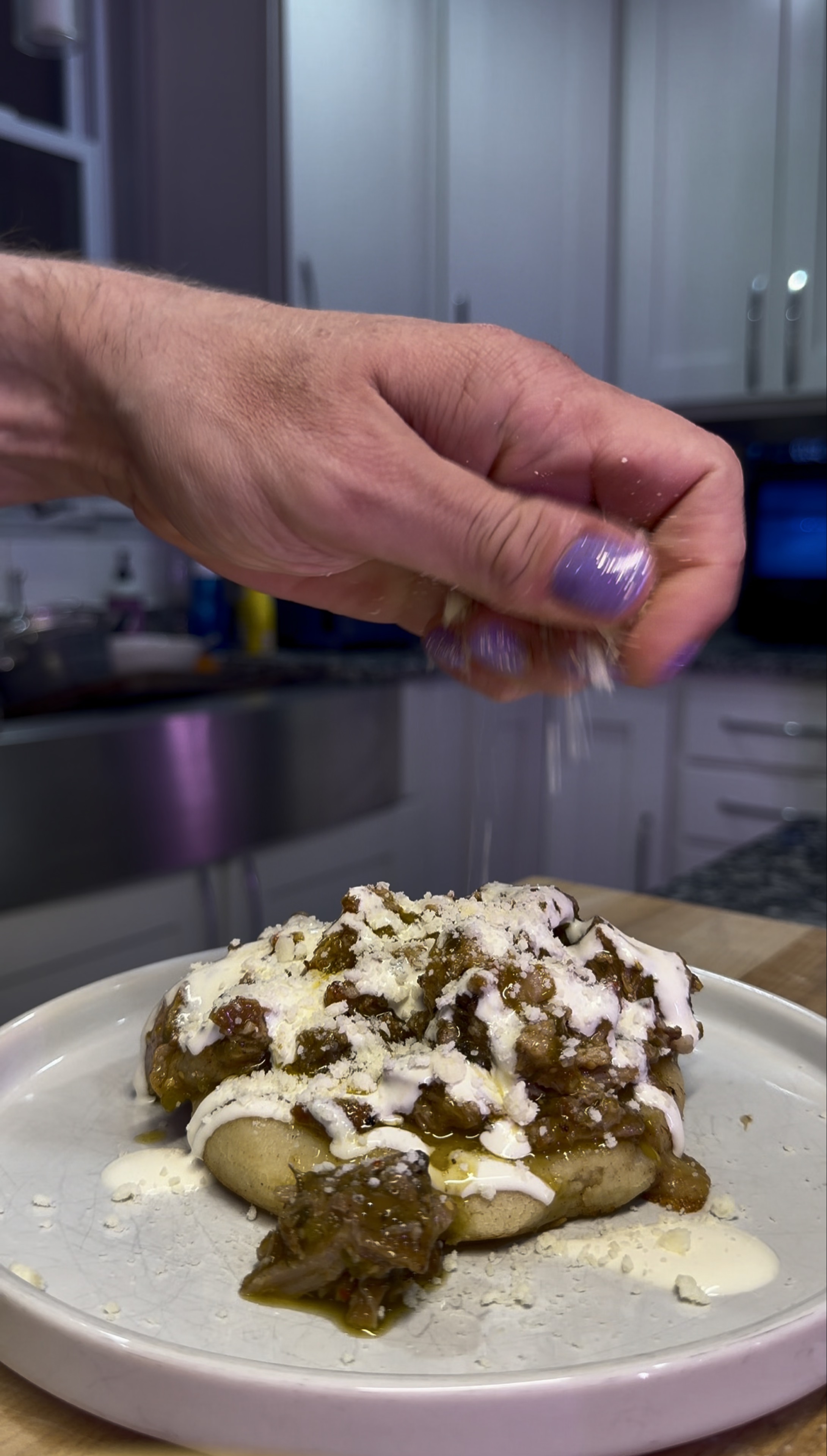 Green chile pork, crema, and cheese spooned over a handmade pupusa